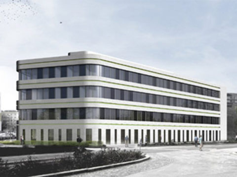 Ein modernes, vierstöckiges Bürogebäude mit Glasfenstern und abgerundeten Ecken steht an einer Straßenkreuzung unter einem leicht bewölkten Himmel.