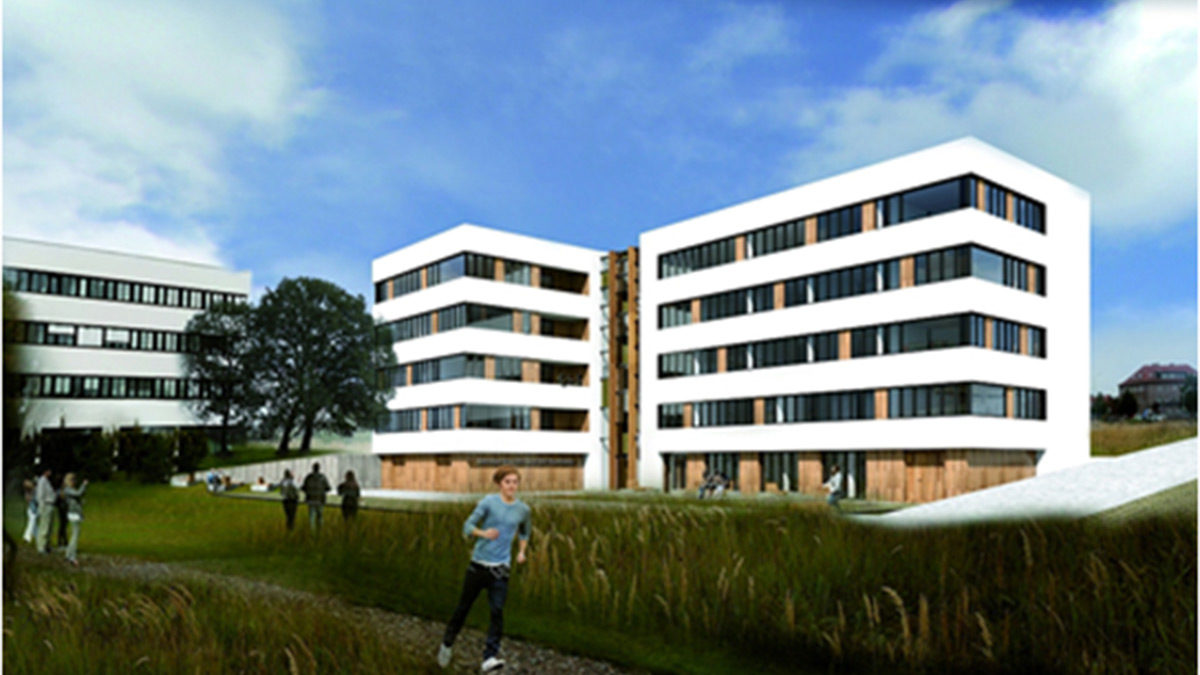 Ein modernes, weißes, mehrstöckiges Gebäude mit großen Fenstern steht in der Nähe einer Grünfläche mit Menschen, die unter einem teilweise bewölkten Himmel spazieren gehen und joggen.