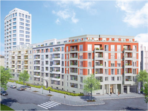 Modernes mehrstöckiges Wohngebäude mit orangefarbener und weißer Fassade, Balkonen und Straßenansicht, mit einem höheren weißen Gebäude im Hintergrund unter klarem Himmel.