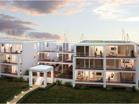 Modernes dreistöckiges Wohnhaus mit großen Fenstern und Balkonen, in Wassernähe mit Booten und Sonnenuntergangshimmel im Hintergrund.