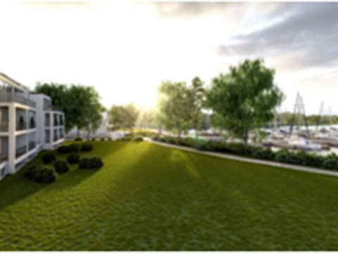 Ein modernes Apartmentgebäude überblickt eine große Rasenfläche mit Bäumen und einem Jachthafen mit Booten im Hintergrund bei Sonnenuntergang.