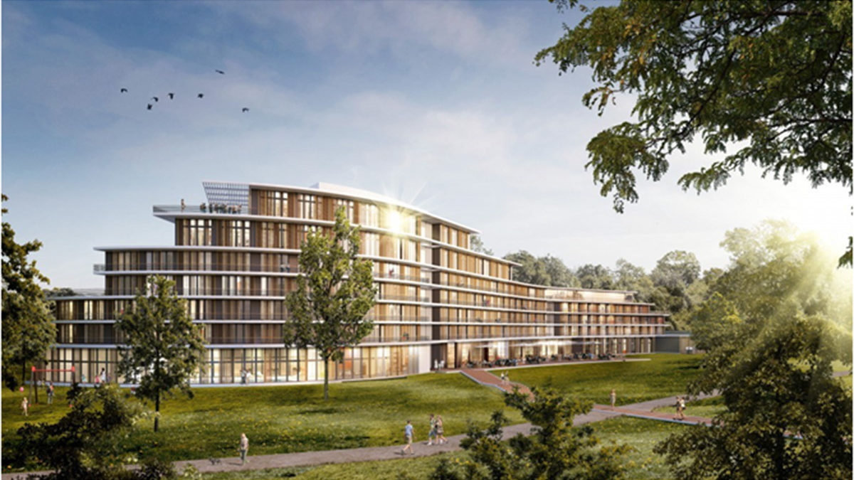 Ein modernes, mehrstöckiges Gebäude mit einer Fassade aus Glas und Holz steht in einem grasbewachsenen Park, umgeben von Bäumen und Menschen, die unter einem sonnigen Himmel auf den nahen Wegen spazieren gehen.